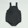A dark gray kids denim romper with a rounded neckline and two patch pockets.
