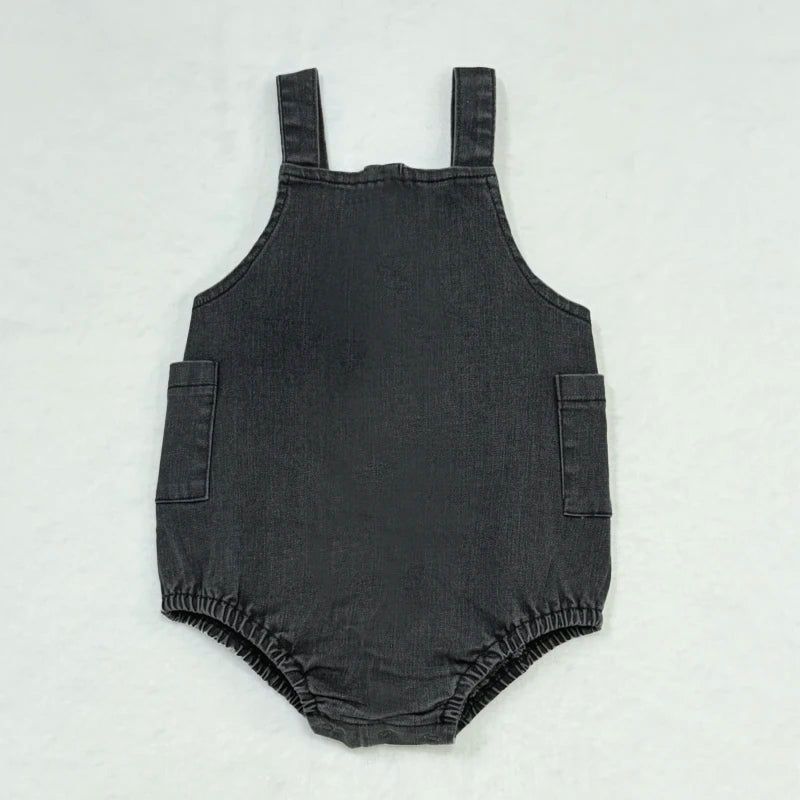 A dark gray kids denim romper with a rounded neckline and two patch pockets.