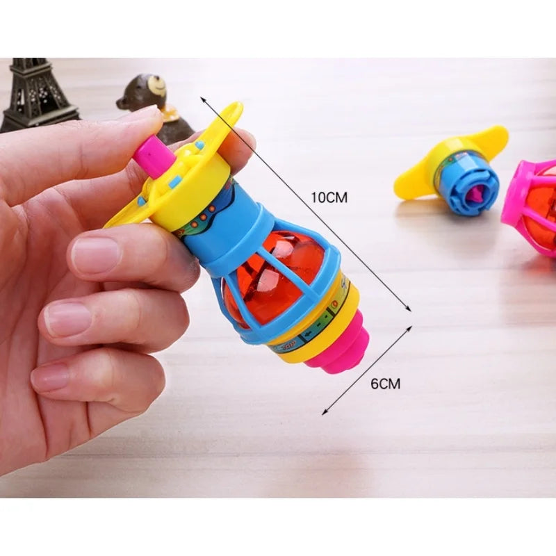A hand holds a glowing spinning top toy with colorful parts and LED lights on a wooden surface.