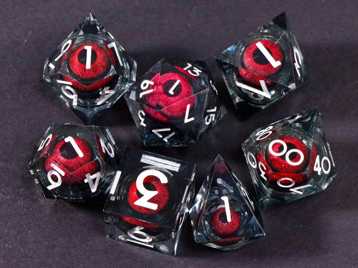 A set of seven liquid core resin polyhedral dice, including a d10, d12, d20, and d40, arranged on a dark surface.