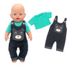 A baby doll wearing a dark denim outfit set including a shirt and overalls with a bear face design.