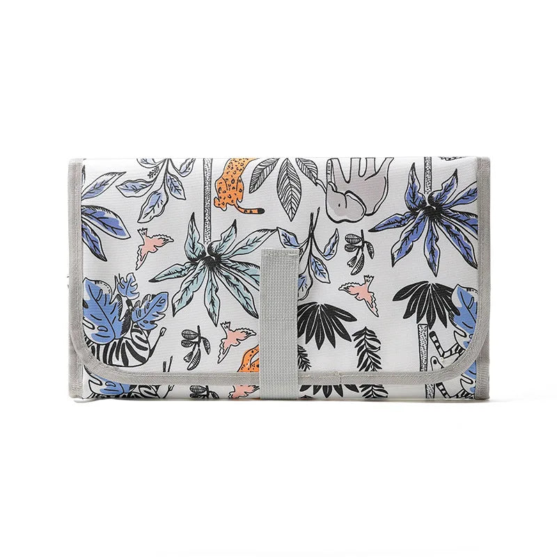 A light gray portable waterproof baby changing mat featuring a botanical leaf pattern and a carry handle.