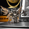 A highly detailed metallic figurine of an armored warrior with wings and a large sword displayed on a dark surface.