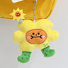 A yellow flower plush pendant doll with green boots and a sun charm hanging from a yellow fabric.