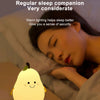 A warm white pear-shaped night light is placed on a bedside table next to a person sleeping.