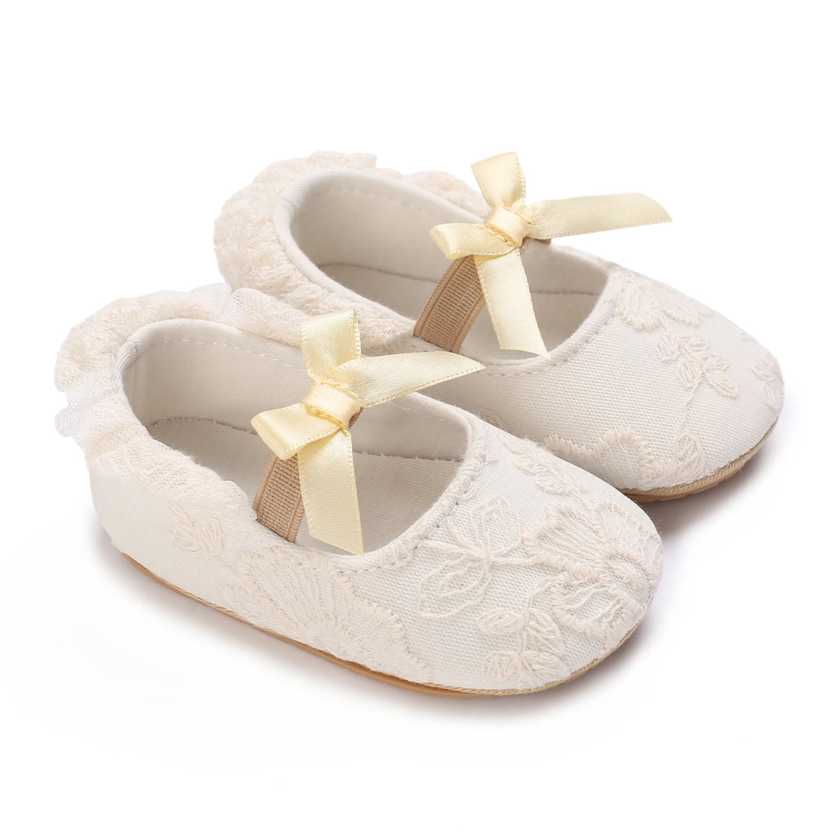Pair of light beige lace-trimmed moccasin shoes for a baby girl with fabric bows