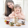 A young girl and woman are setting up a wooden pretend play tea party set with various cups and saucers.