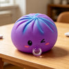 A purple, squishy dumpling-shaped stress relief toy with a clear bubble feature resting on a wooden table.