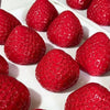 A close-up view of several bright red strawberries arranged on a white surface.