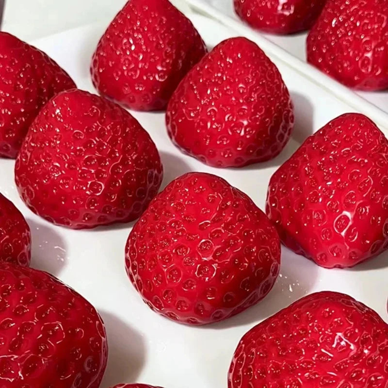 A close-up view of several bright red strawberries arranged on a white surface.