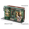 A miniature dollhouse kit featuring a green shop facade with glass windows and warm lighting.
