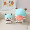 A pair of cute panda bear plush toys, one light blue and one orange, sitting on a white sofa.
