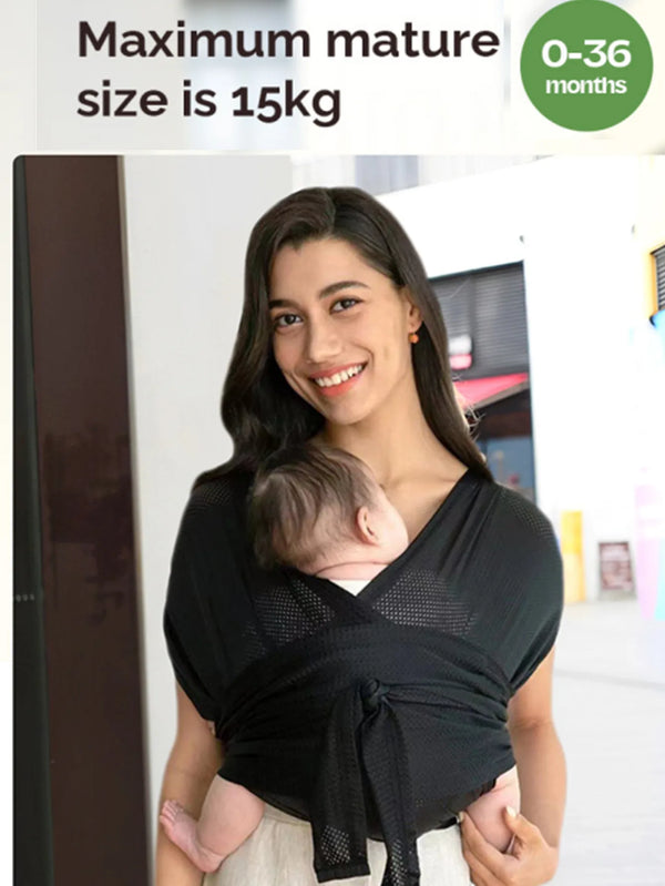A woman is holding a baby in a black X-shaped sling carrier for newborn support.