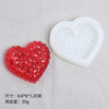 A set of silicone resin molds shaped like a red heart and a white heart resting on a gray surface.