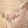 Close-up of sparkling 5D diamond nail art stickers arranged on a pink background.
