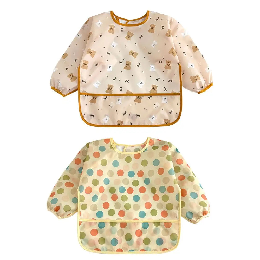 A set of two light-colored baby bibs with a floral pattern, one featuring small brown animals and the other with multi-colore