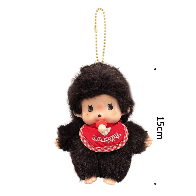 A small, dark brown plush cartoon character with a round face and red clothing is shown hanging from a gold chain.