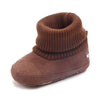 A brown knitted baby winter snow boot with a fuzzy ball accent, shown from the side.