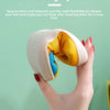 A close-up of a soft yellow and blue cartoon dinosaur plush slipper being held by a hand.