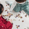 A child is assembling a wooden jigsaw puzzle featuring various animal shapes on a light surface.