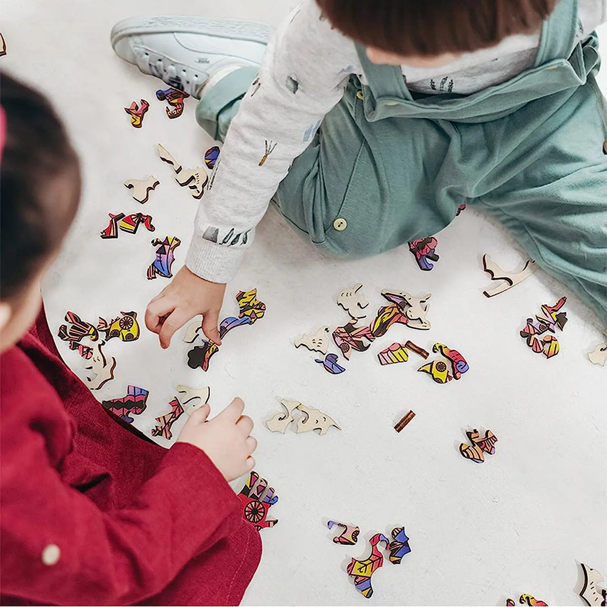 A child is assembling a wooden jigsaw puzzle featuring various animal shapes on a light surface.