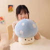 A person is holding a light blue mushroom plush pillow with white polka dots on a white table.