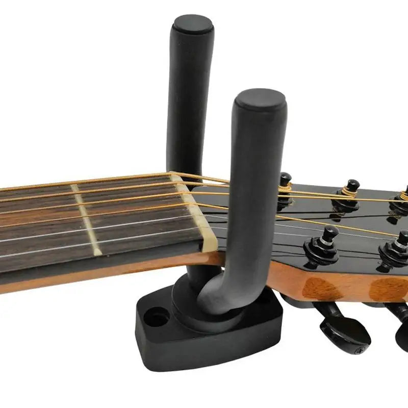 A black guitar wall mount hanger with soft padding and tuning pegs is shown on a wooden guitar neck.