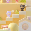 A collection of cute cat mini figurines in various colors and poses displayed on a light yellow shelf with white steps.