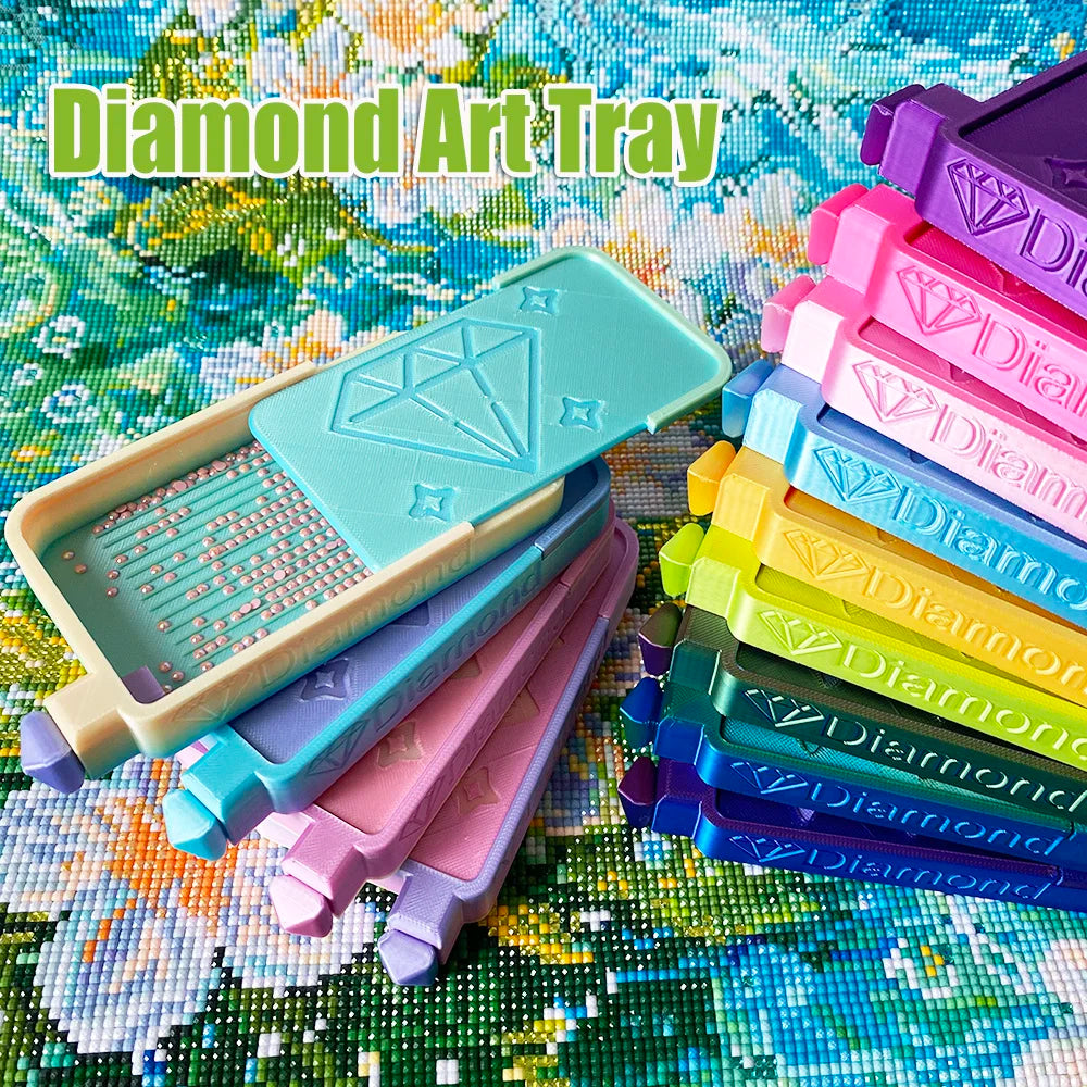 A diamond art tray with multiple storage compartments and colored plastic tiles is displayed on a textured surface.