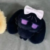 A dark blue plush keychain featuring purple sunglasses and a white bow.