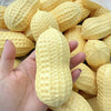 A hand holds a large yellow squishy stress ball shaped like a peanut, surrounded by many similar items.