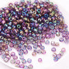 A pile of iridescent purple and blue glass rice beads for DIY jewelry and crafting.