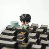 A close-up shot of a black collectible keycap blind box featuring a character with dark hair and red accents.