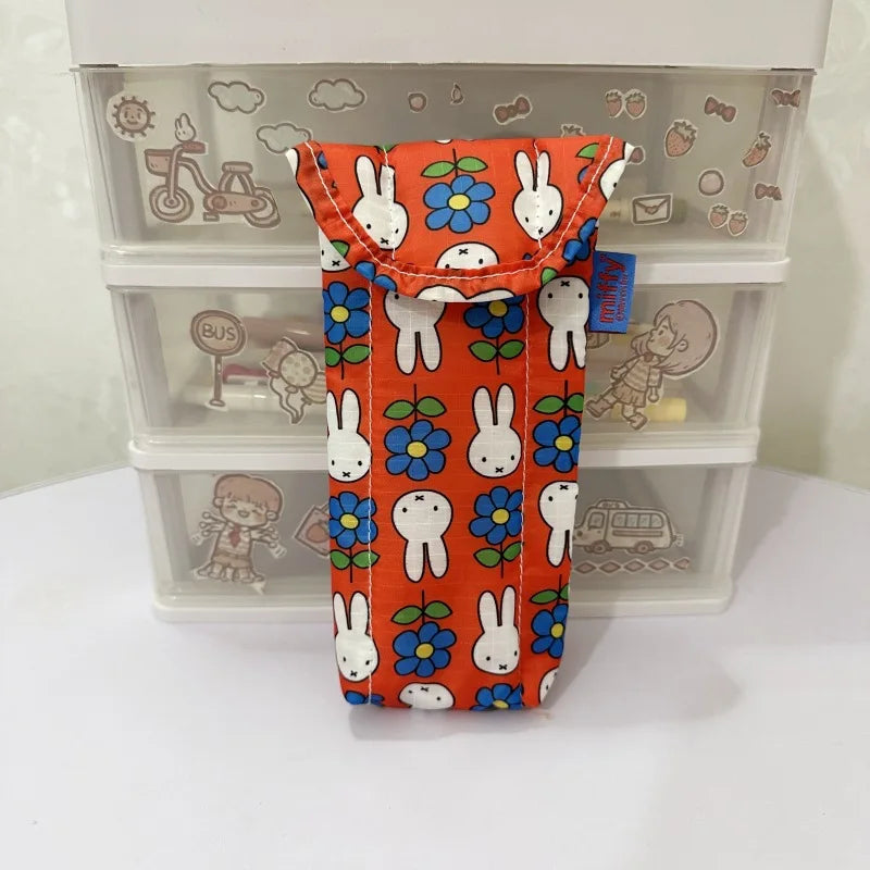 An orange fabric storage bag featuring repeating Miffy rabbit patterns, displayed in a clear plastic storage box.