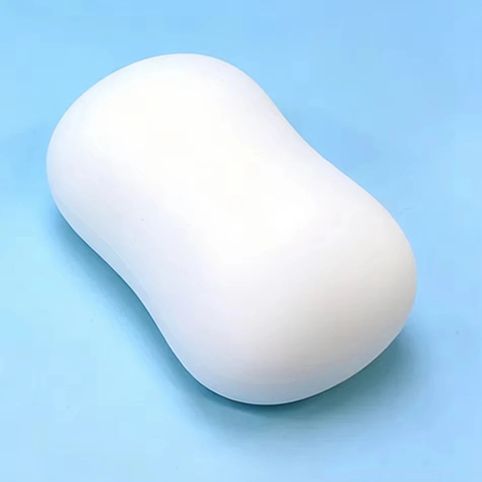 A smooth, white, oval-shaped squishy stress relief toy resting on a light blue surface.