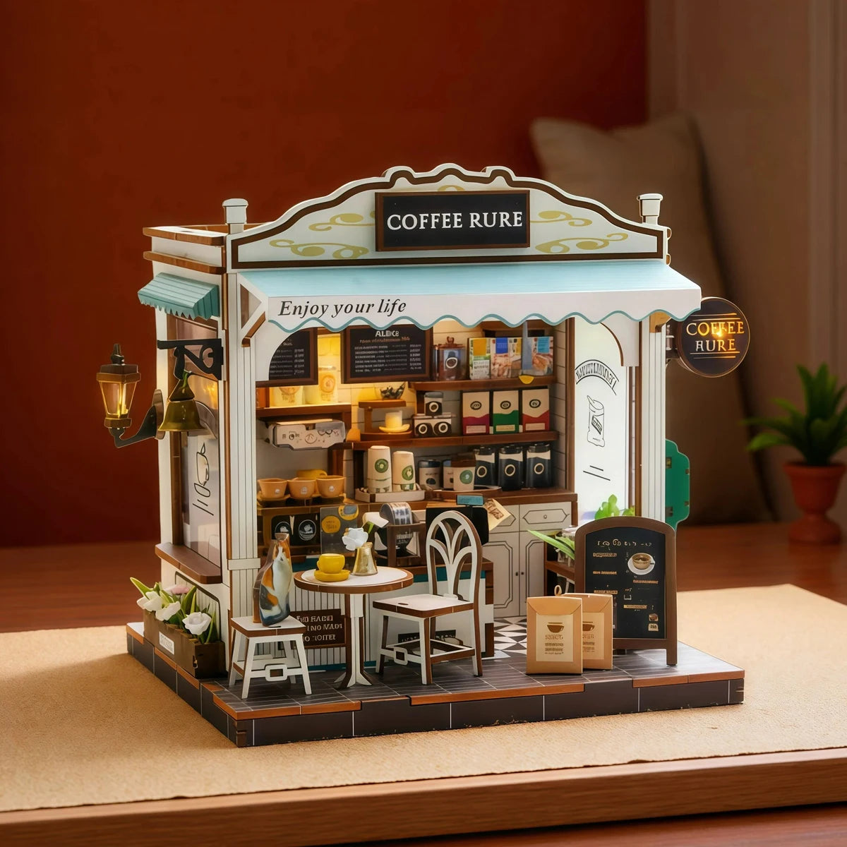 A detailed miniature wooden coffee shop house kit featuring a counter, shelves stocked with goods, and signage.
