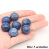 A hand holds several smooth blue aventurine crystal spheres.