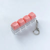A clear acrylic keychain featuring four pink clicky key buttons.