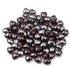 A pile of dark brown heart-shaped acrylic beads for jewelry making