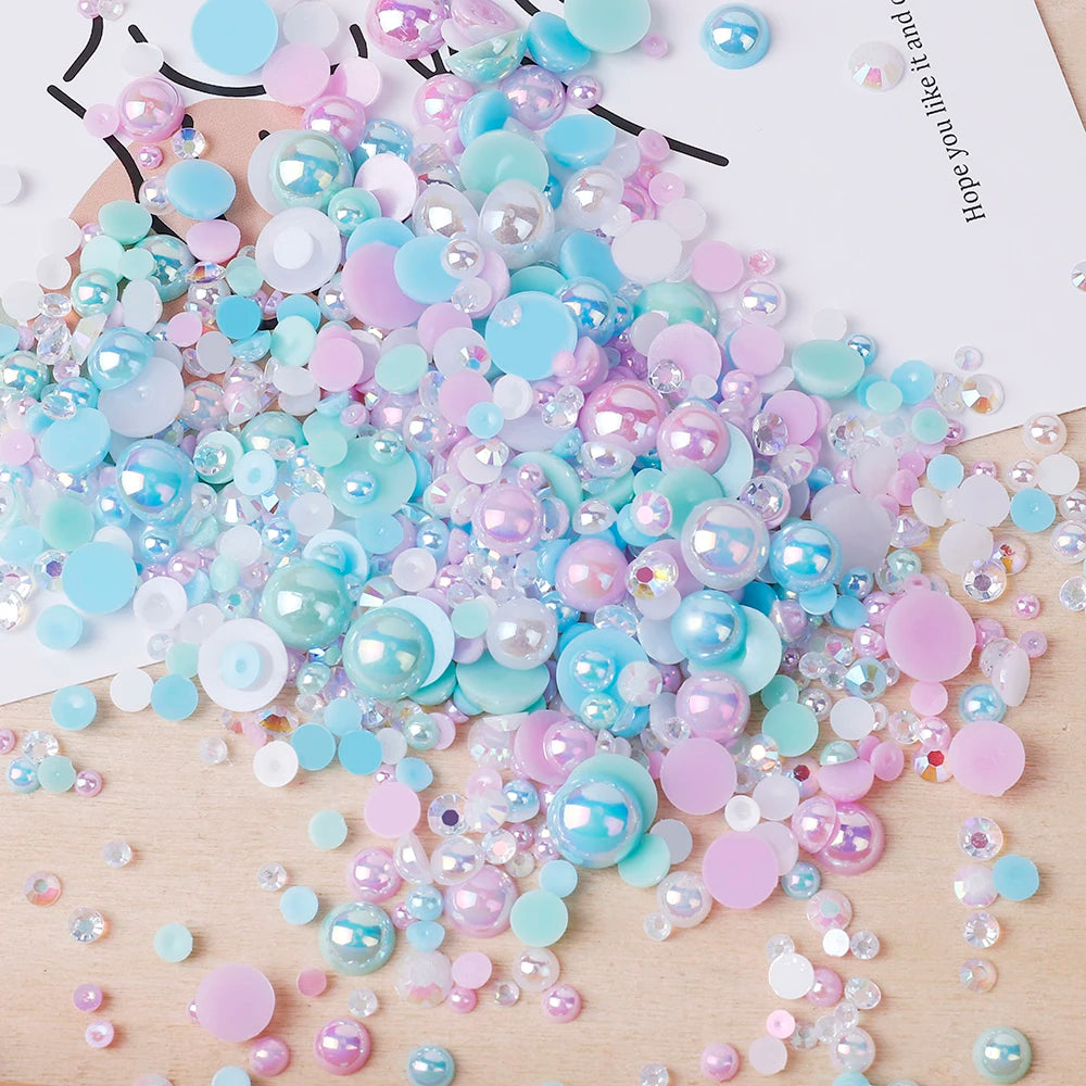A colorful mix of iridescent resin and rhinestone pearls in shades of blue, pink, and purple scattered on a wooden surface.