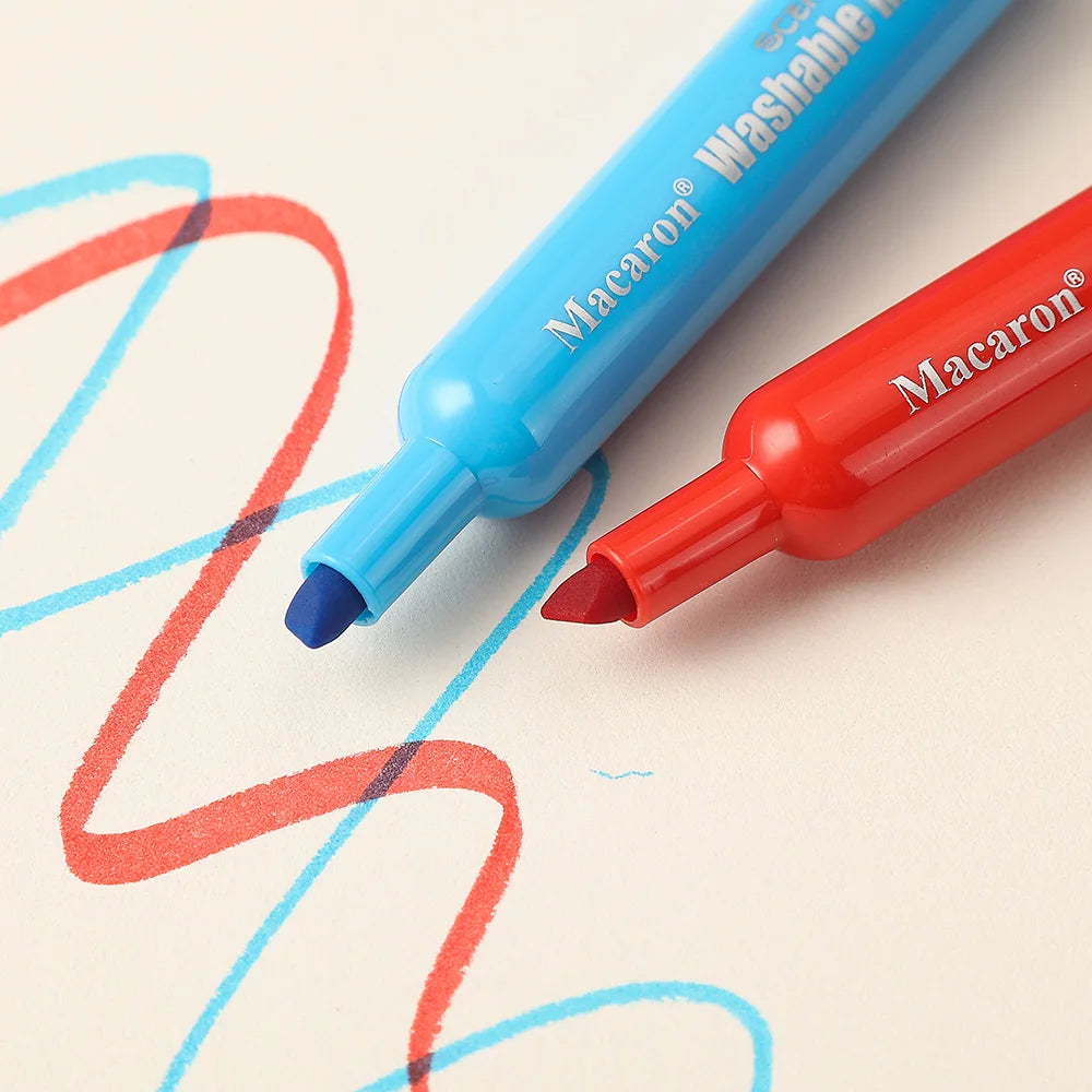Deux marqueurs lavables Macaron, un bleu et un rouge, écrivent sur une feuille de papier blanc.