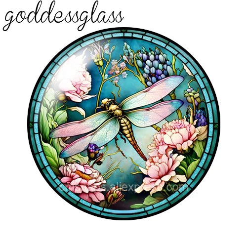 A round glass cabochon featuring a detailed floral and insect design in shades of green, purple, and pink.