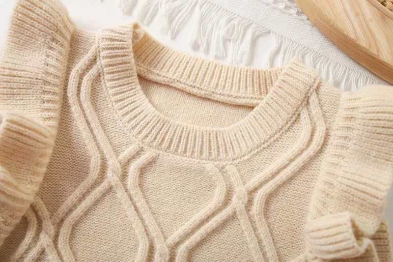 A beige knit sweater vest featuring a flower shape design and ruffled edges.