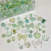 A collection of mixed clear and green acrylic bow and flower beads for jewelry making.