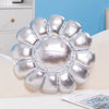 A silver plush cushion shaped like a large sunflower resting on a white surface.