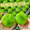 A hand holds a bright green watermelon kiwi squishy stress ball fidget toy.