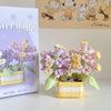 A miniature flower bouquet building block set featuring purple and yellow flowers and green blocks.