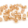 A collection of small, faceted bicone crystal glass beads in a warm amber or honey color.