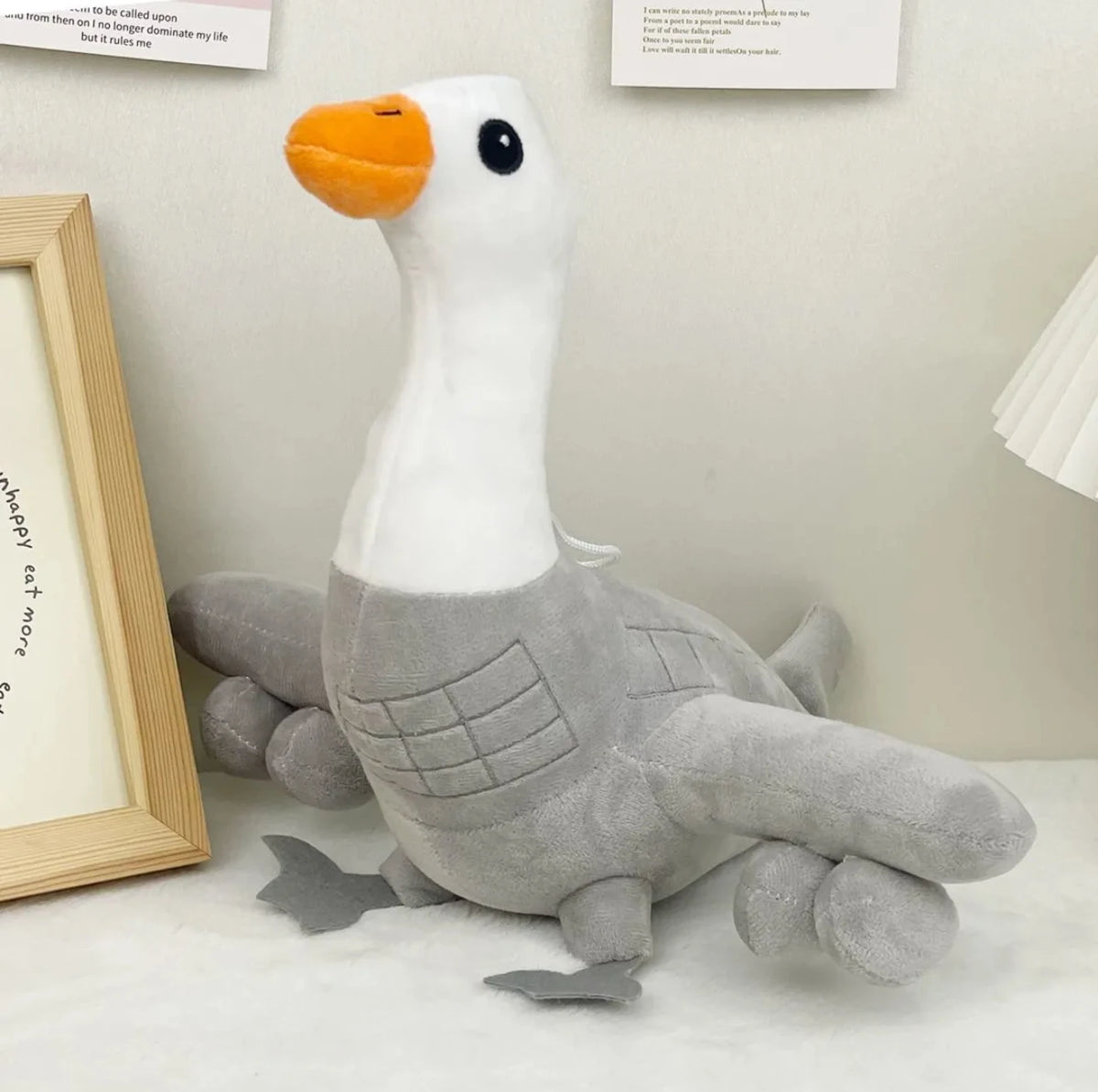 A white and gray shark plush toy with an orange snout sitting on a white surface.