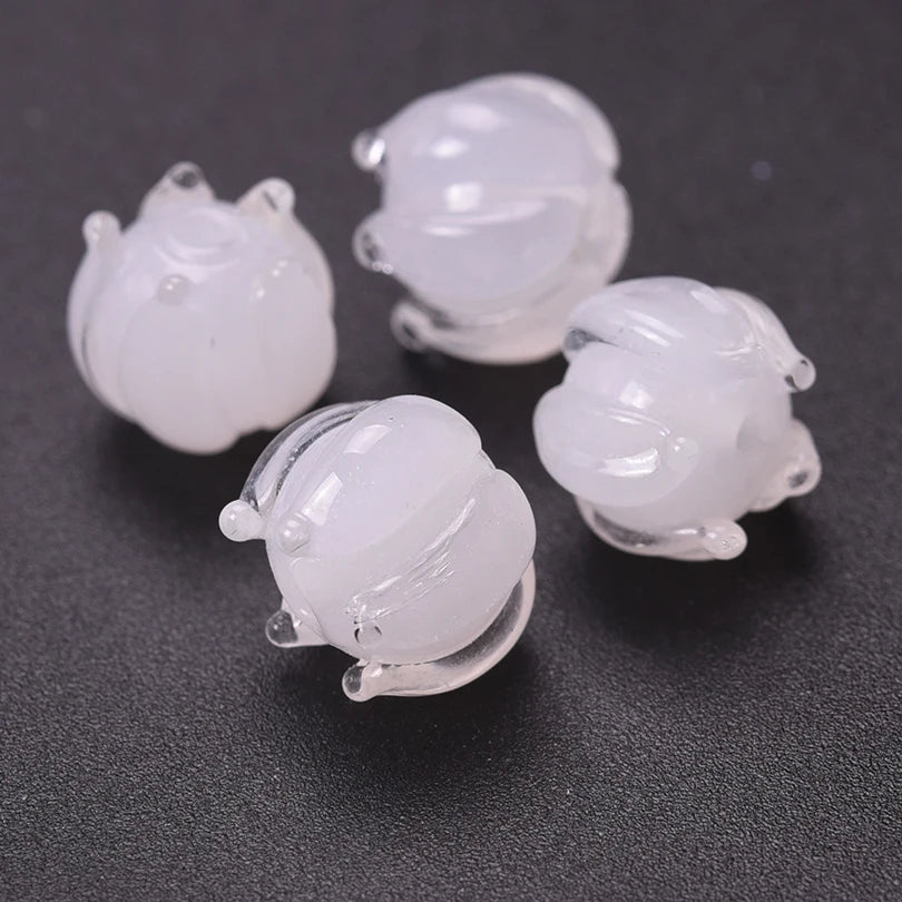Several clear glass charm pendants shaped like lily of the valley blooms are displayed on a dark surface.